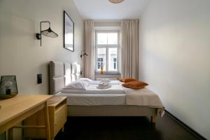een slaapkamer met een bed, een bureau en een raam bij Apartments Wróblewskiego Street in Krakau