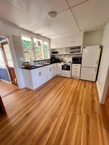 cocina con armarios blancos y suelo de madera en Moon House en Queenstown