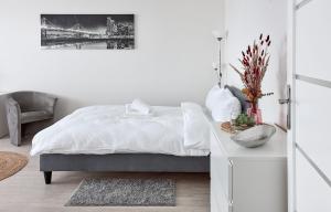 a white bedroom with a bed and a table at Osiedle Zwycięstwa Chic Studio in Poznań