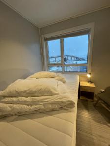 uma cama num quarto com uma grande janela em Vestfjordgata Apartment 1 em Svolvær