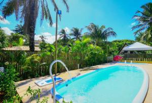 una piscina en un complejo con palmeras en Pousada Ecologica Bangalo de Praia, en Itacimirim
