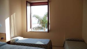 una camera con due letti e una finestra con una palma di Villaggio Hydra a Marina di Casalvelino