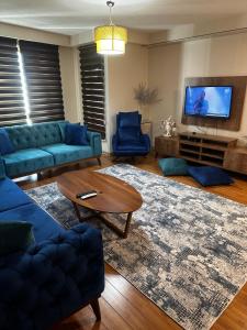 sala de estar con sofás azules y TV en Atasehir Rezidans, en Estambul