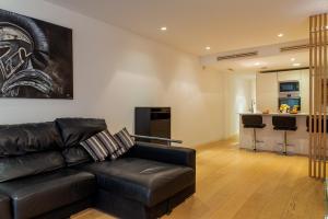 a living room with a black leather couch and a kitchen at MyFlats San Fernando in Alicante