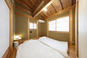 鐮倉的住宿－一棟貸しの宿 寂香庵，卧室设有一张白色大床和两个窗户。
