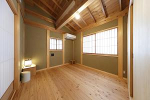 an empty room with wooden floors and two windows at 一棟貸しの宿 寂香庵 in Kamakura