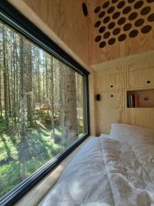 a bedroom with a large window in a forest at Treetop Ekne - Hytte i skogen med hengebru in Levanger