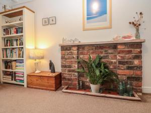 a living room with a brick fireplace with a plant at Shell Seeker Cottage in Bridlington