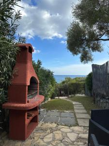 piec z czerwonej cegły siedzący na patio w obiekcie Domus Tom Apartment with sea view Villasimius w mieście Villasimius