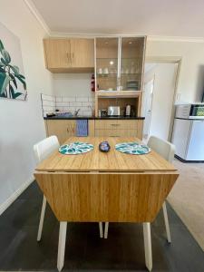 une cuisine avec une table en bois entourée de chaises. dans l'établissement Emu Retreat B&B, à Tailem Bend