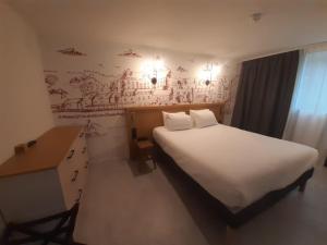 a bedroom with a white bed and a desk and a wall at L'Escale Marine, The Originals Relais in Crozon