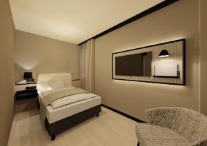 a bedroom with a bed and a tv and a chair at Residenz Wessinger, Neu-Isenburg in Neu Isenburg