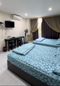 two beds in a room with a desk and a table at 西子楼 CZI Budget Hotel Sungai Siput in Sungai Siput