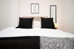 a bedroom with a bed with white sheets and black pillows at Central Charming and Contemporary 2Br Apartment in Swindon