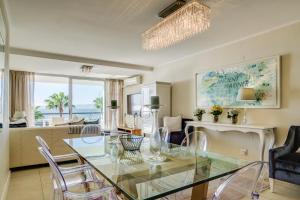 a dining room and living room with a glass table and chairs at Aqua Views in Cape Town