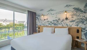 a bedroom with a large bed and a large window at L'Escale Marine, The Originals Relais in Crozon