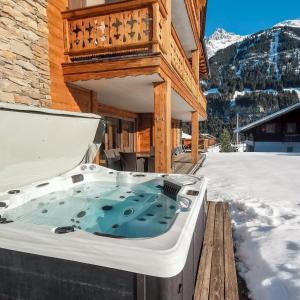 una bañera de hidromasaje en la cubierta de una casa en la nieve en Chalet Soleil by Mrs Miggins, en Champéry