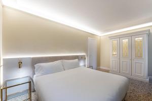 een witte slaapkamer met een bed en een deur bij San Vio Palace Luxury Apartments in Venetië