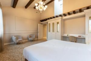 Un dormitorio con una gran cama blanca y sillas en San Vio Palace Luxury Apartments, en Venecia