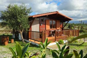 eine Blockhütte mit einer Terrasse und einem Baum in der Unterkunft Vila da Laje - Onde a Natureza o envolve - Serra da Estrela in Oliveira do Hospital
