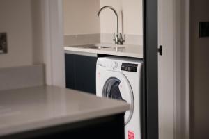 a kitchen with a washing machine and a sink at Three The Stables at Corrstown Village in Portrush