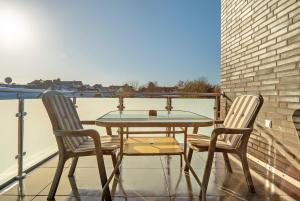 einen Glastisch und zwei Stühle auf dem Balkon in der Unterkunft Neubau Ferienwohnung mit Balkon in Gronau