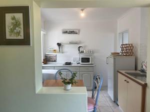 a small white kitchen with a table and a microwave at Harbour Cottage Kalk Bay in Cape Town