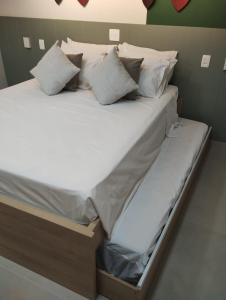 a large bed with white sheets and pillows at Flat Amarilis Apartamento 202 in Riviera de São Lourenço