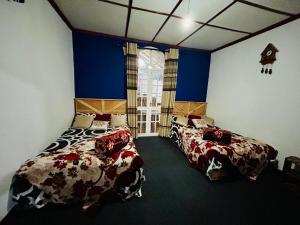 Duas camas num quarto com paredes azuis em Crystal Mounts em Nuwara Eliya