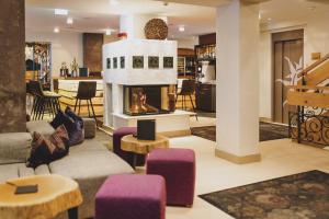 a living room with a fireplace and purple chairs at Hotel DIE SONNE in Saalbach Hinterglemm