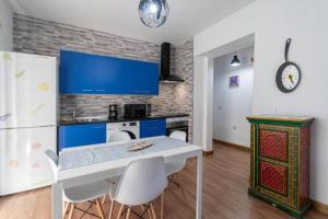 uma cozinha com armários azuis e uma mesa e cadeiras em El Sueño de Cádiz by Gades Gestión em Cádiz