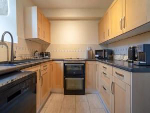 a kitchen with wooden cabinets and a black appliance at Pass the Keys Converted 17th century barn with garden parking in Cheltenham