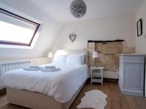 um quarto com uma grande cama branca e uma janela em Pass the Keys Converted 17th century barn with garden parking em Cheltenham