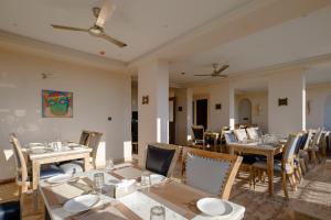 Infinia Stays - A Luxury Boutique Hotel في أودايبور: مطعم بطاولات وكراسي و لوحة على الحائط