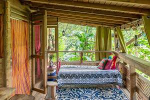 Zimmer mit einem Bett auf einer Veranda in der Unterkunft Adorable, Cosy Wooden Bauhinia Cottage in Roseau