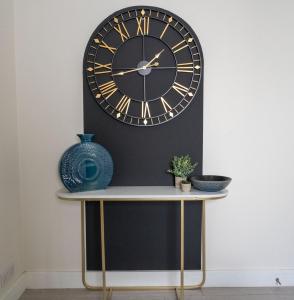 a clock on a wall with a table and a vase at Free Parking | Free Wifi | Stylish in Newport