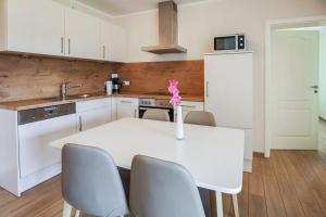 a white kitchen with a white table and chairs at Buedlfarm-Huehnerstall in Sahrensdorf