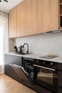 a kitchen with a black oven and wooden cabinets at NEW! High-street stylish flat (NDK) FREE Parking in Sofia