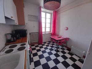 cocina con mesa roja y suelo a cuadros en L'appart de Babou REZ DE CHAUSSEE parking free draps wifi, en Thiers