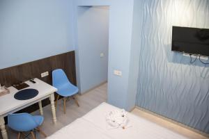 a room with a table and blue chairs and a tv at AG Hotel in Almaty