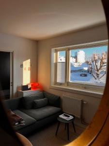 a living room with a couch and a large window at Hygge houses I Studio apartment in Lillestrøm I Solo or Couple in Lillestrøm