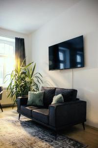 a black couch in a living room with a plant at NUWILU ONE - Apartment mit Balkon im Herzen Erfurts - Magenta TV- Netflix - Disney in Erfurt