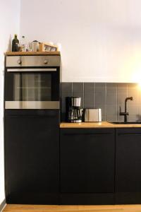 a kitchen with a black oven and a sink at NUWILU ONE - Apartment mit Balkon im Herzen Erfurts - Magenta TV- Netflix - Disney in Erfurt