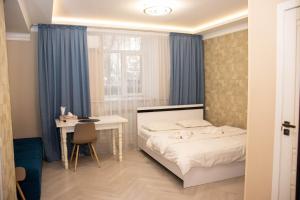 Schlafzimmer mit einem Bett, einem Schreibtisch und einem Fenster in der Unterkunft AG Hotel in Almaty