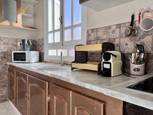 a kitchen with a counter with a sink and a microwave at Dar Zakaria Toursitic Area in Tozeur