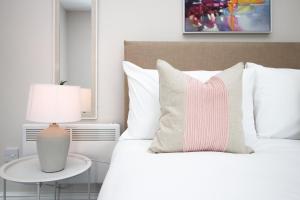 een slaapkamer met een wit bed en een roze gestreept kussen bij Archer Road Penarth Free parking in Cardiff