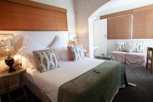 1 dormitorio con 1 cama blanca grande con almohadas en The Grosvenor Guest House & Self Catering, en Simonʼs Town