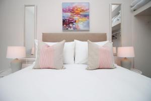 Un dormitorio con una cama blanca con almohadas rosas y blancas en Archer Road Penarth Free parking en Cardiff