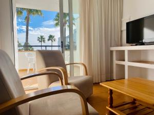 a living room with a television and a table and chairs at Apartamentos Tamarindos Peñiscola in Peñíscola