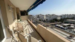 einen Balkon mit Stühlen und einem Tisch sowie Stadtblick in der Unterkunft Puerto Banús, seaviews, 2 bedrooms and parking in Marbella